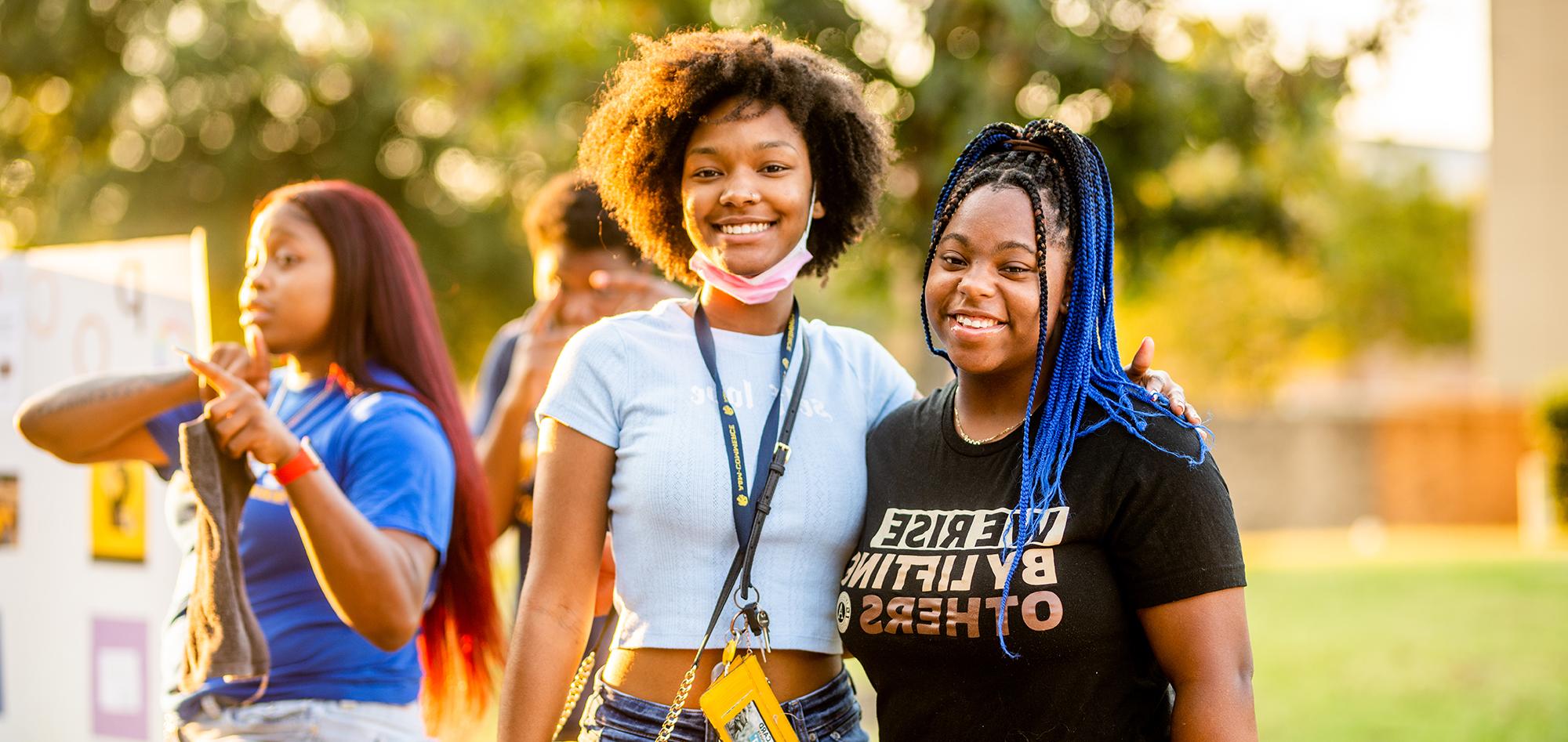 Two students smiling on campus during sunset.